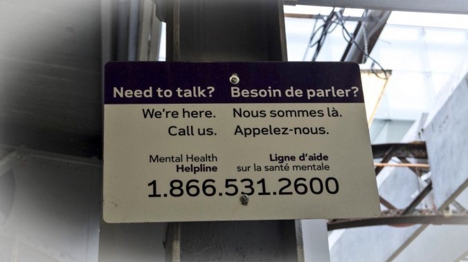 Metrolinx sign on train platform with crisis phoneline information